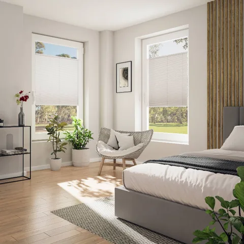 Helles Schlafzimmer mit weißen Plissees an zwei Fenstern